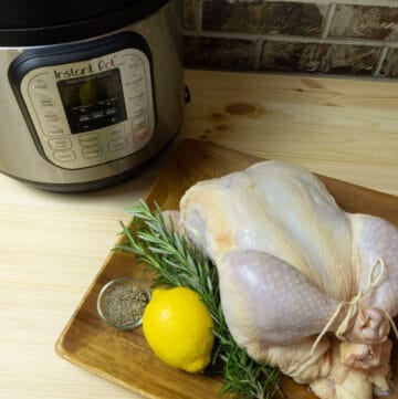 Raw whole chicken on a plate with aromatics next to an Instant Pot pressure cooker
