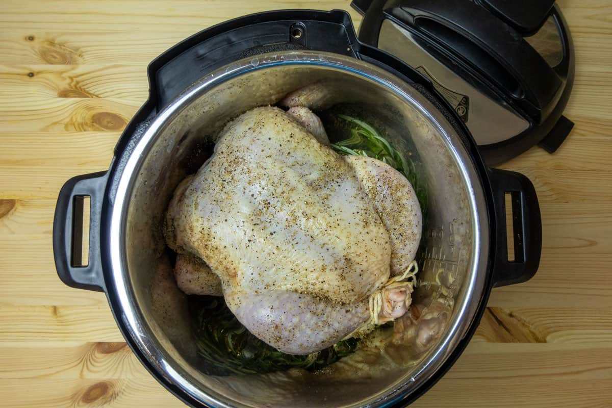 Raw whole chicken in Instant Pot with pepper and salt and the lid