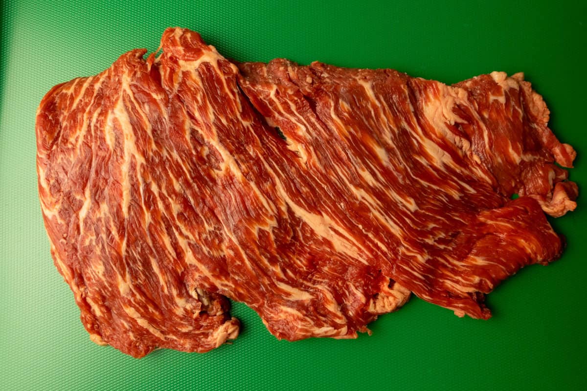 Uncut, well-marbled flap meat on a cutting board. 