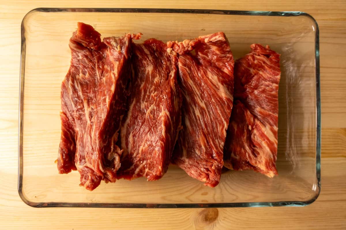 Flap meat cut into 3-inch strips in a pan. 
