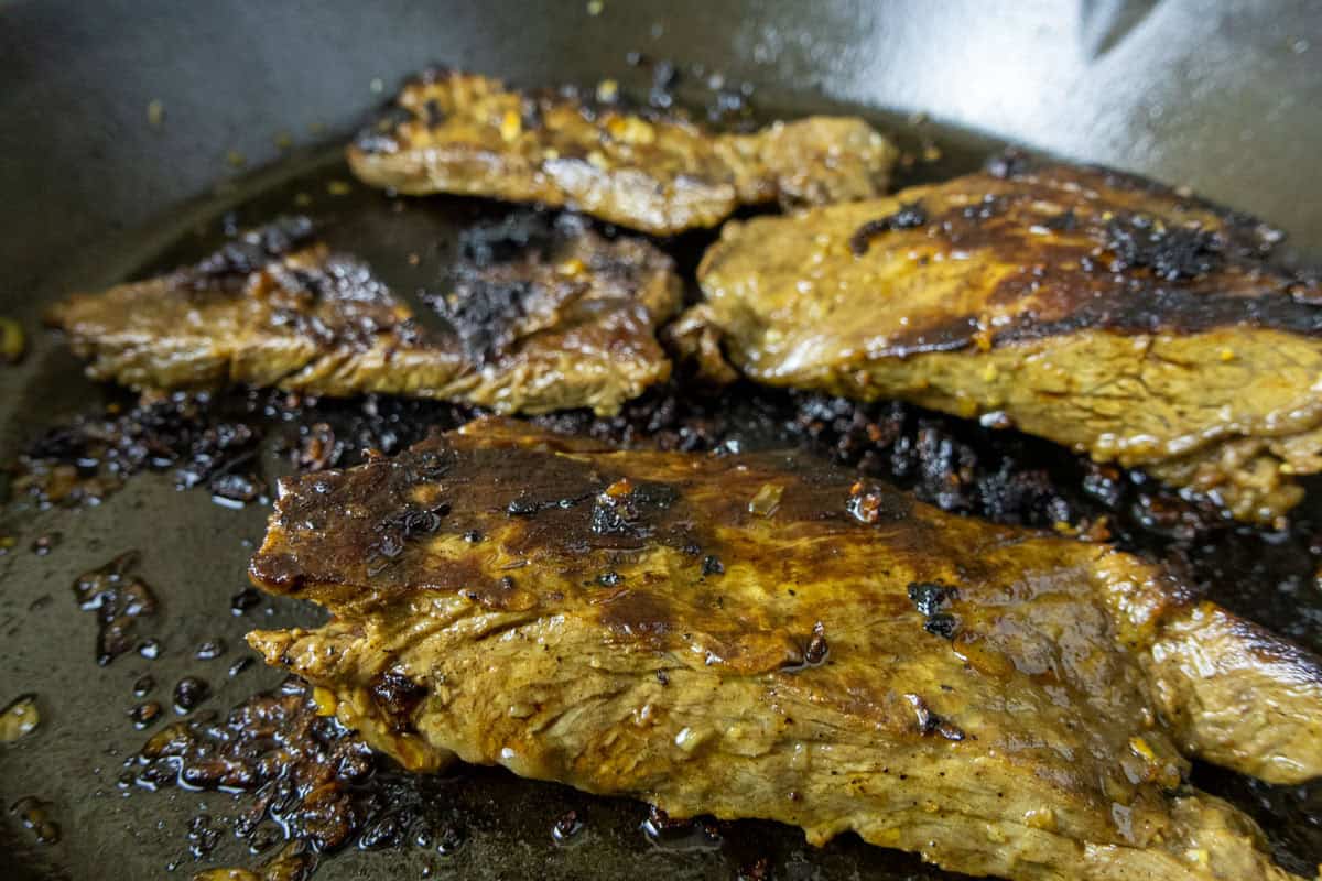 Carne asada cooking in a cast iron pan. 