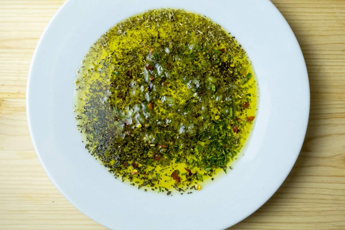A plate with herbs and oil mixed together.
