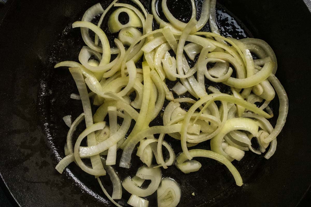 Onions in a cast iron beginning to cook.