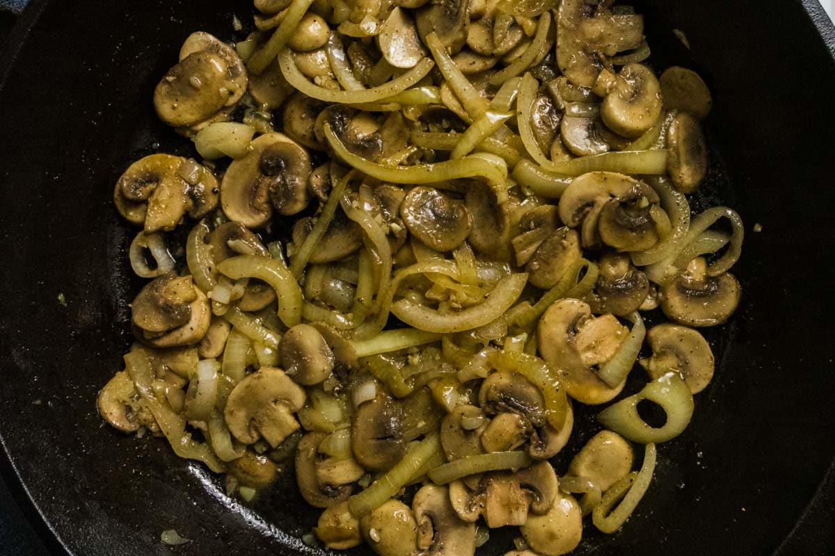 Mushrooms and onions as they're cooking, browning, and crisping.