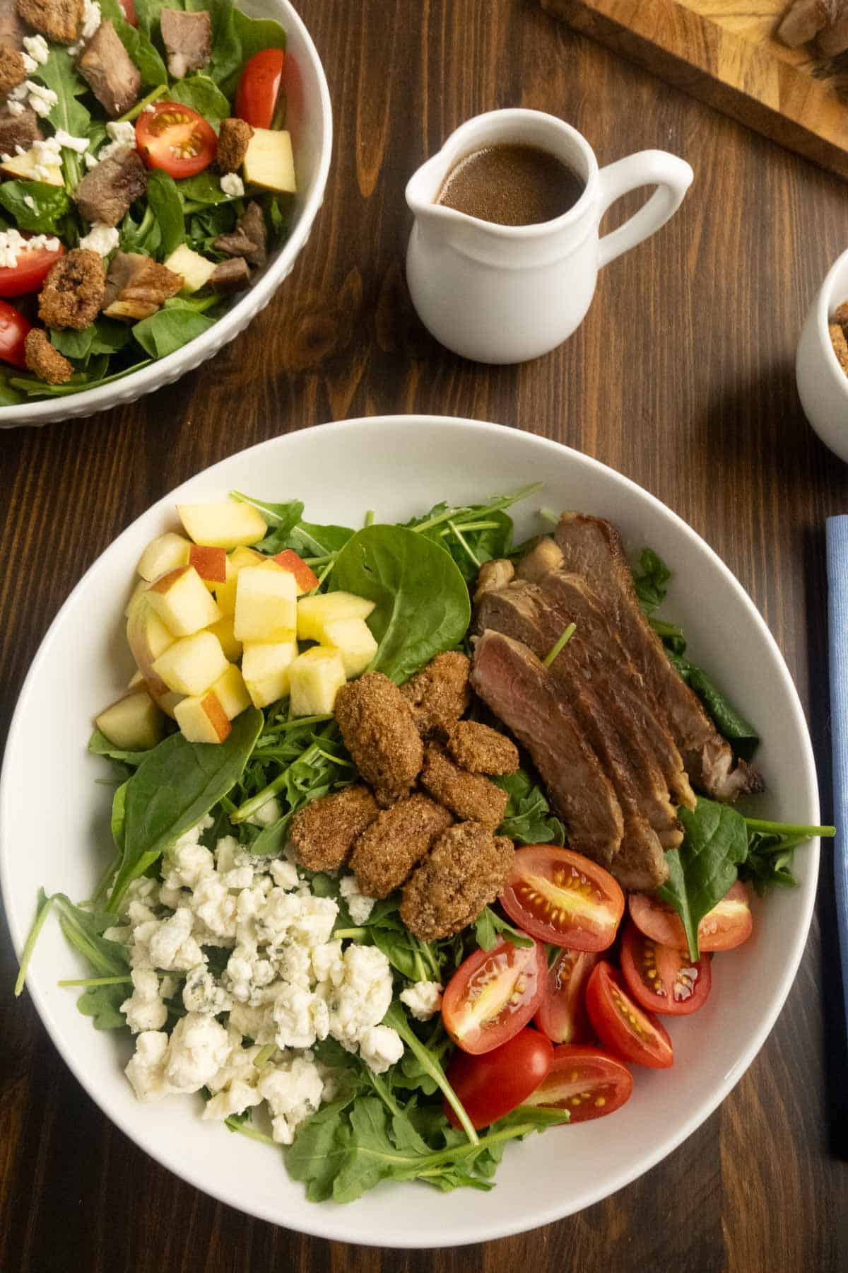 Arugula and spinach salad with steak in a bowl with ingredients in sections. 