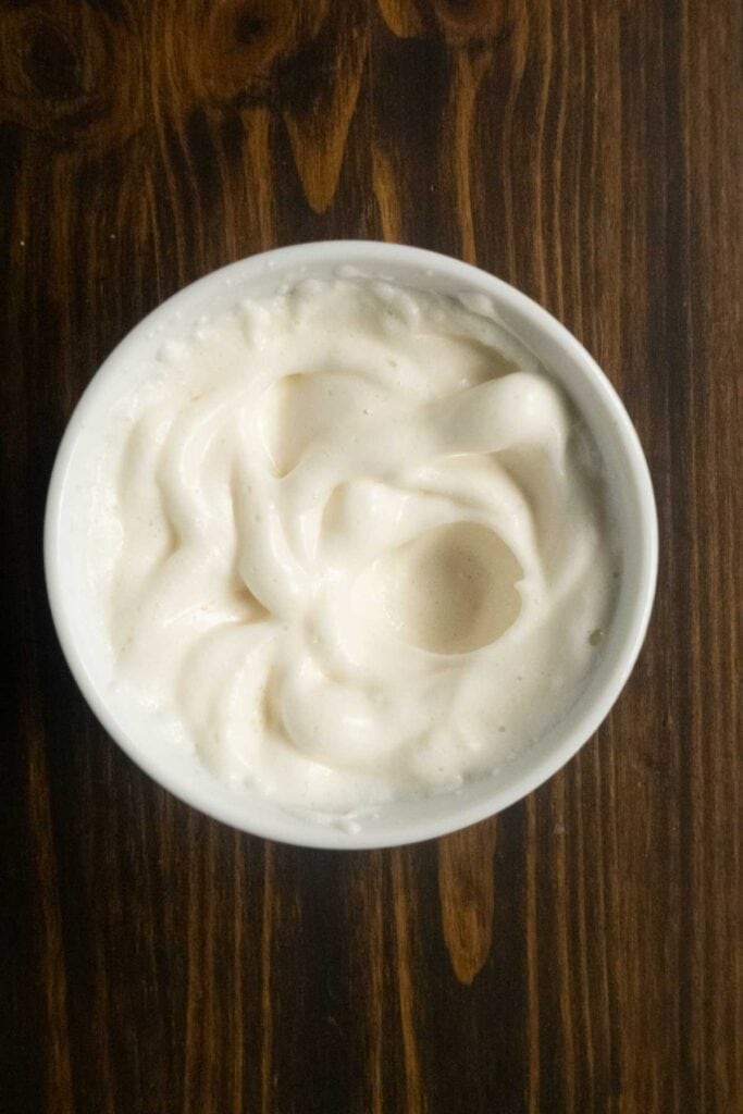 Egg white at soft peaks in a bowl after being whipped with a milk frother. 