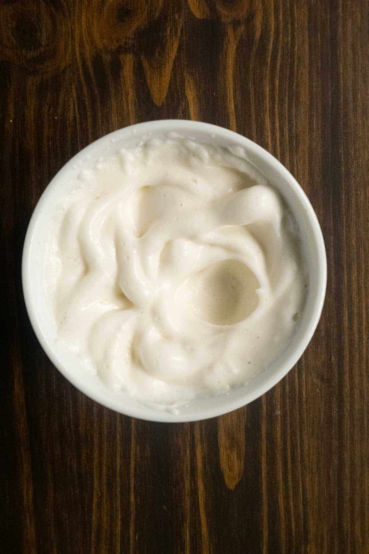 Egg white at soft peaks in a bowl after being whipped with a milk frother.