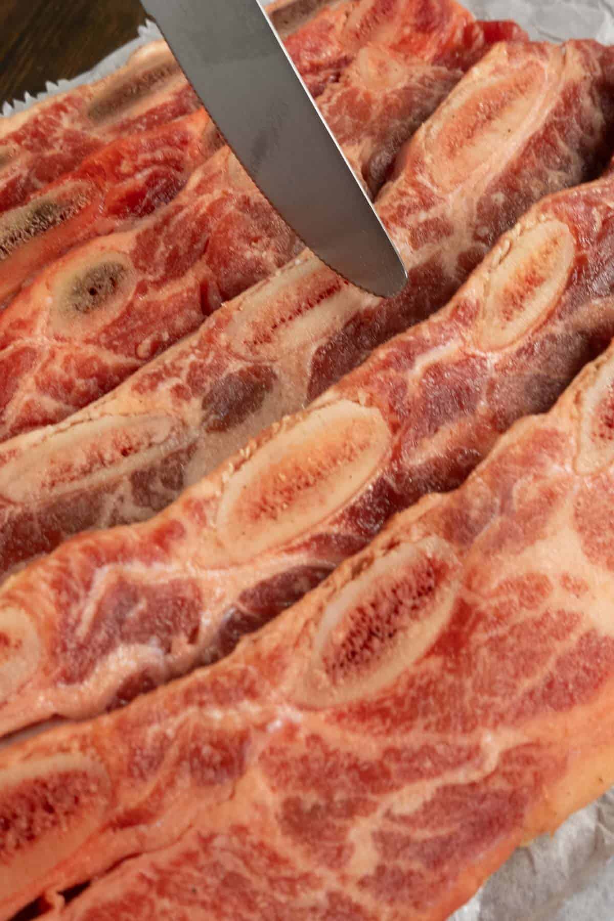 A butter knife starting to scrape bone fragments off of a beef rib.