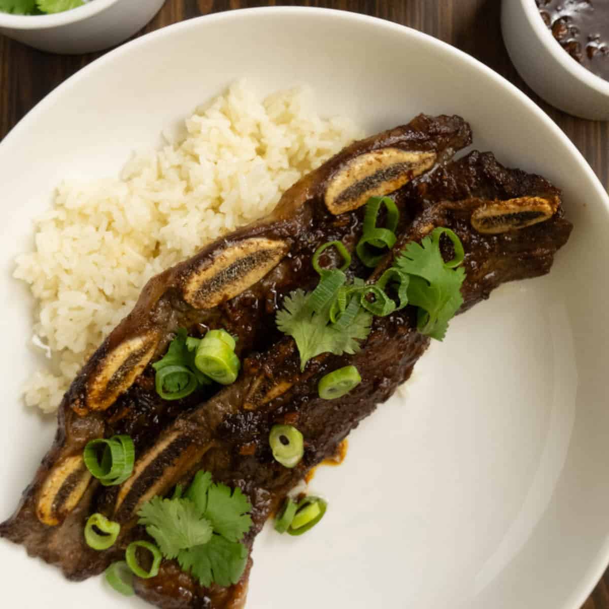 Flanken Beef Short Ribs on a plate with rice garnished with cilantro and green onions.