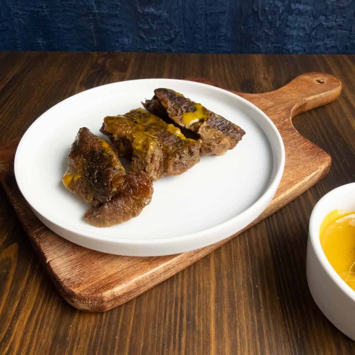 Boneless beef ribs on a plate about to be sauced.