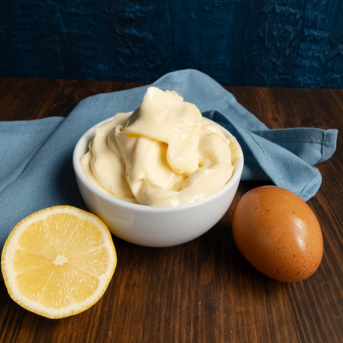 Avocado Mayo with pasteurized eggs in a bowl with lemon and an egg beside it.