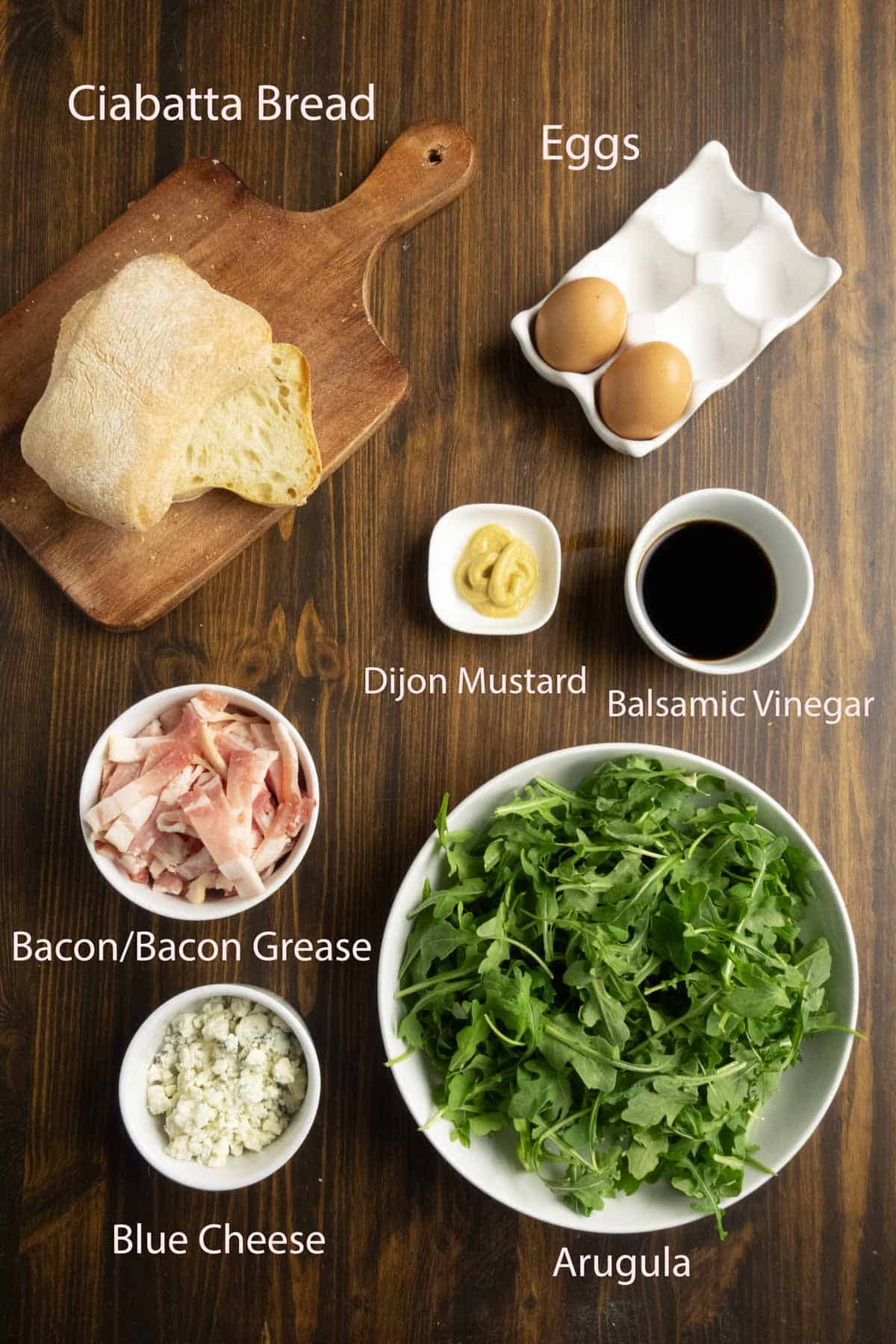 Ingredient shot of ciabatta, eggs, bacon, arugula, and blue cheese.