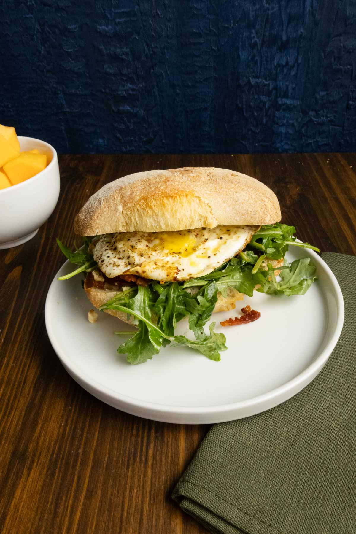 Fried egg ciabatta sandwich with fruit.
