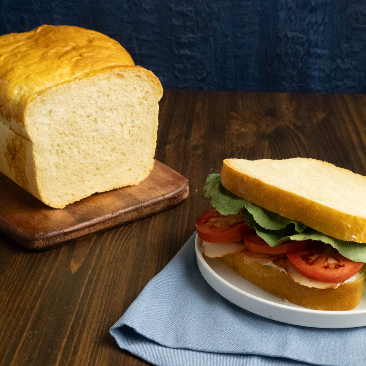 A loaf of sandwich bread and a turkey sandwich on a plate.