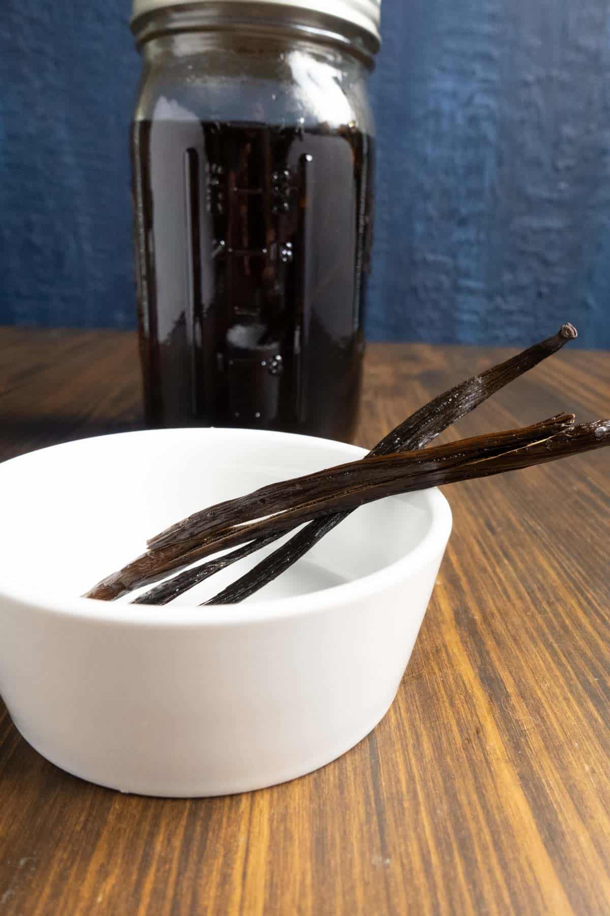 Jar of vanilla extract and vanilla beans on the side.