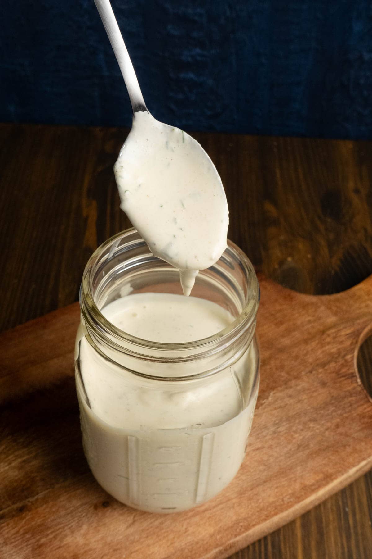 Herby ranch dressing on a spoon over a mason jar.