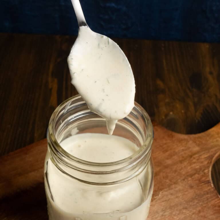 Mason jar filled with herby ranch dressing with a spoonful of dressing.