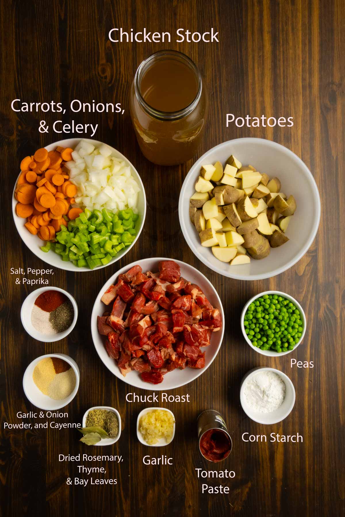 Ingredient shot of chuck roast, onion, carrots, celery, spices, peas, and potatoes.