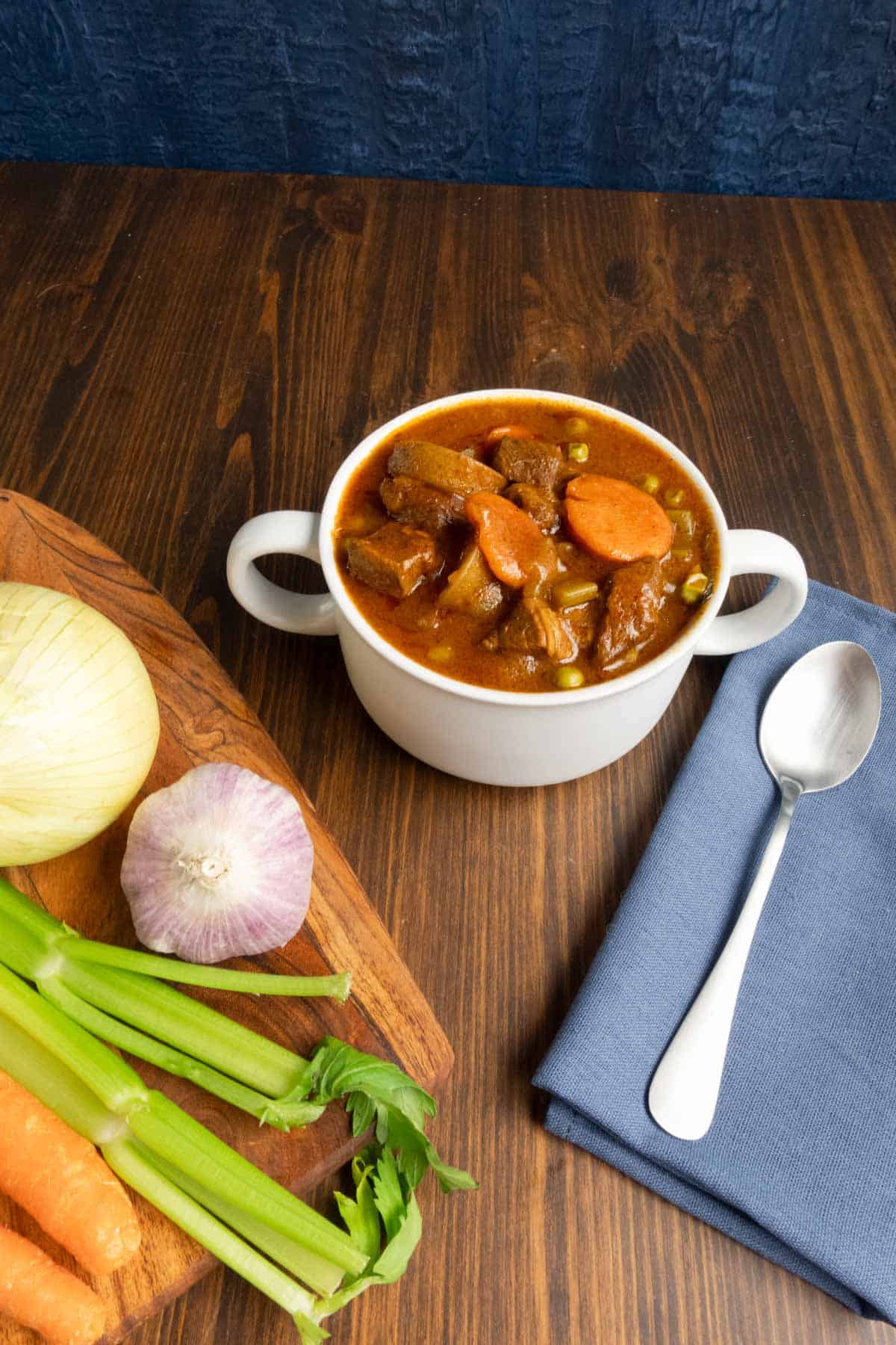 Stovetop beef stew with vegetables behind it.