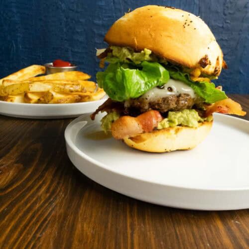 Bacon guacamole burger on a plate looking gorgeous.