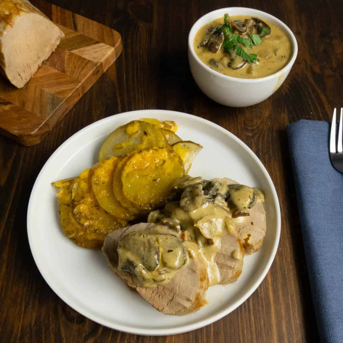 Roasted pork tenderloin on a plate with mushroom, Dijon mustard sauce and potatoes gratin .