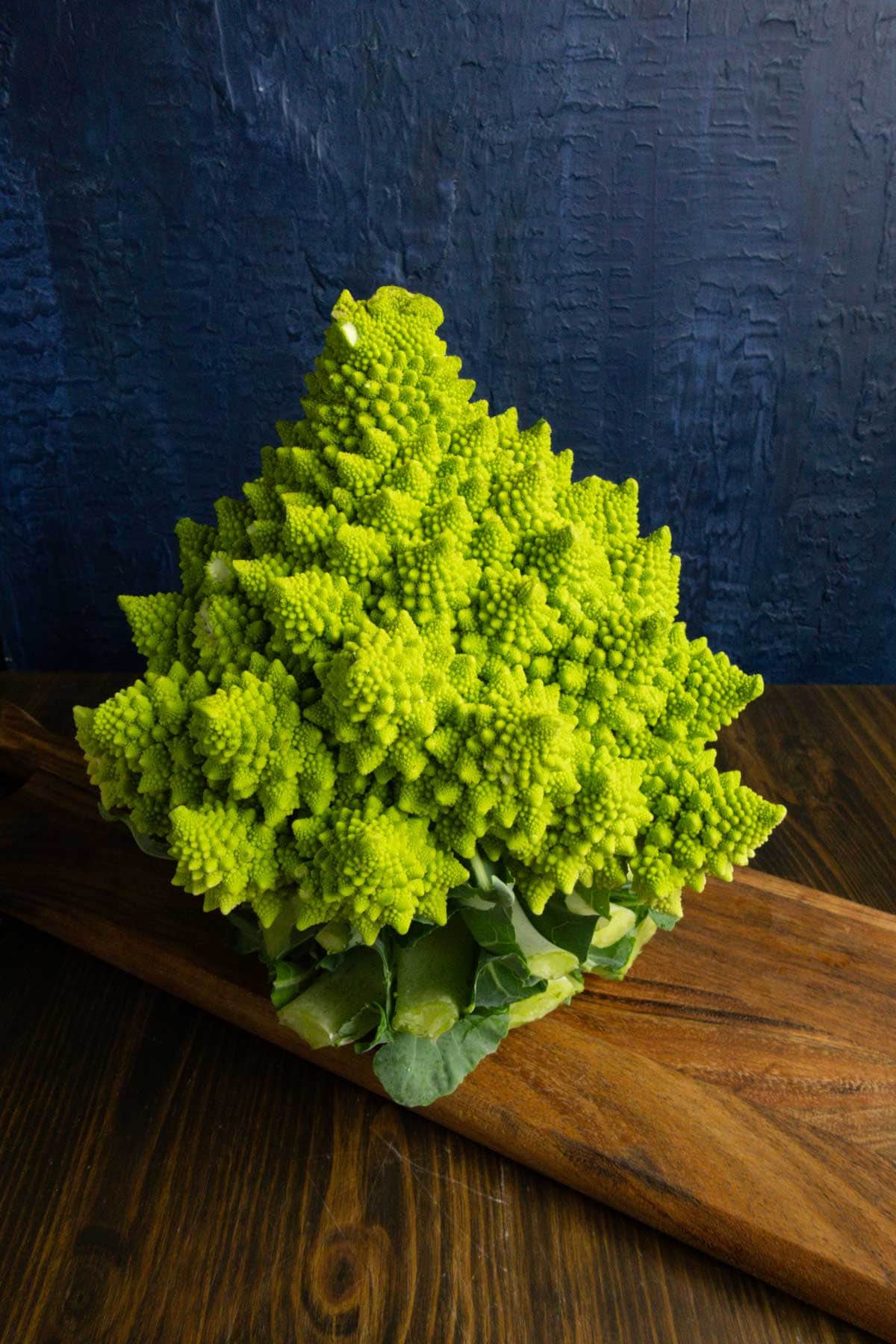 An uncooked Romanesco head on a cutting board.