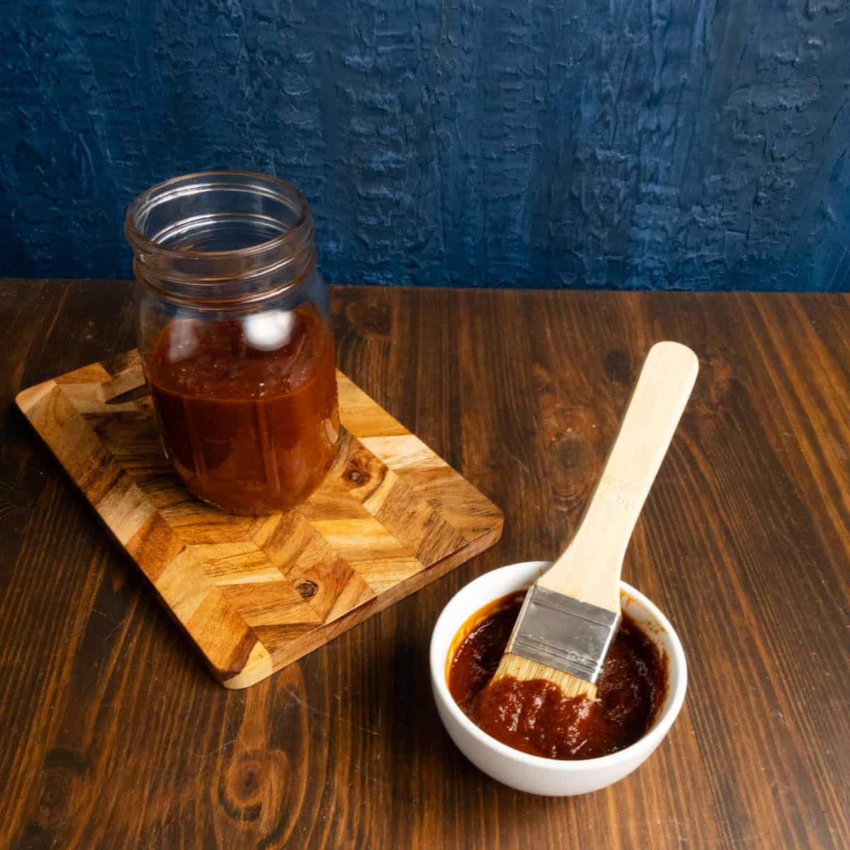 Chipotle barbecue sauce in a small mason jar and in a small bowl with a basting brush.