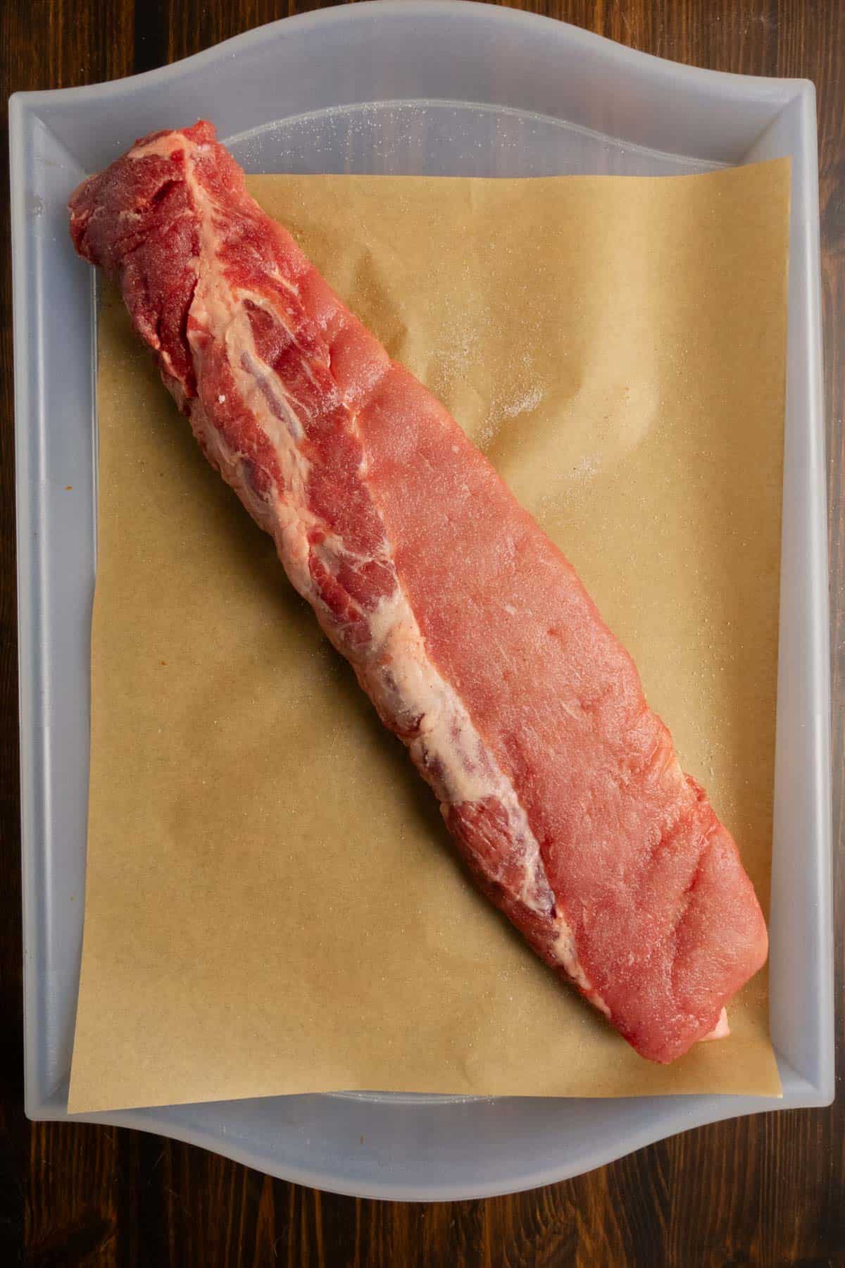 Whole rack of ribs on a tray with salt on it.