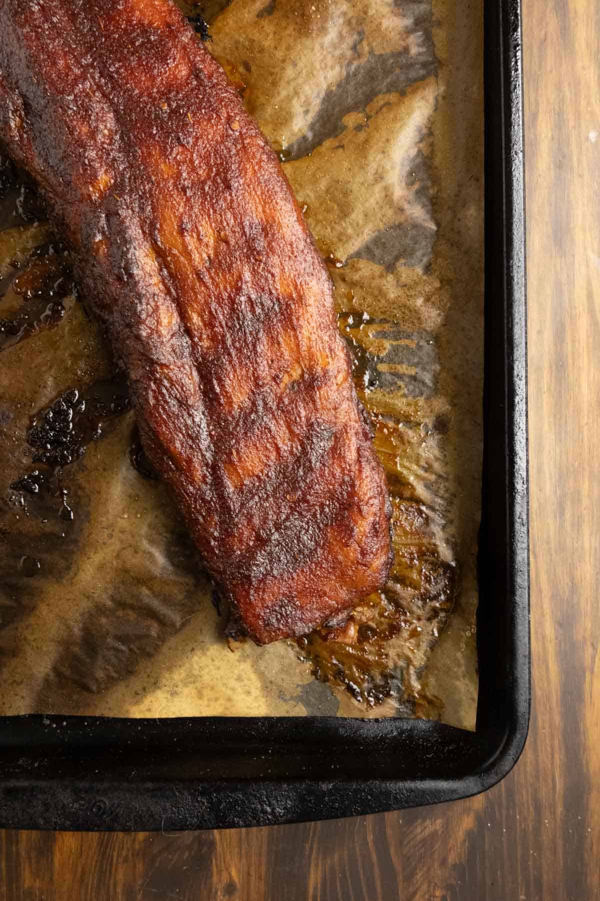 Close up on the bottom of the rack of cooked ribs with sauce.