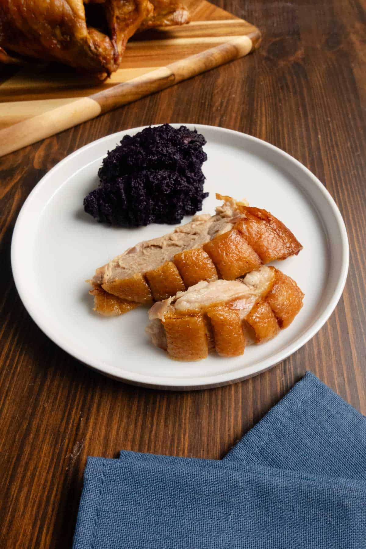 Sliced duck breast on a plate with purple sweet potatoes.