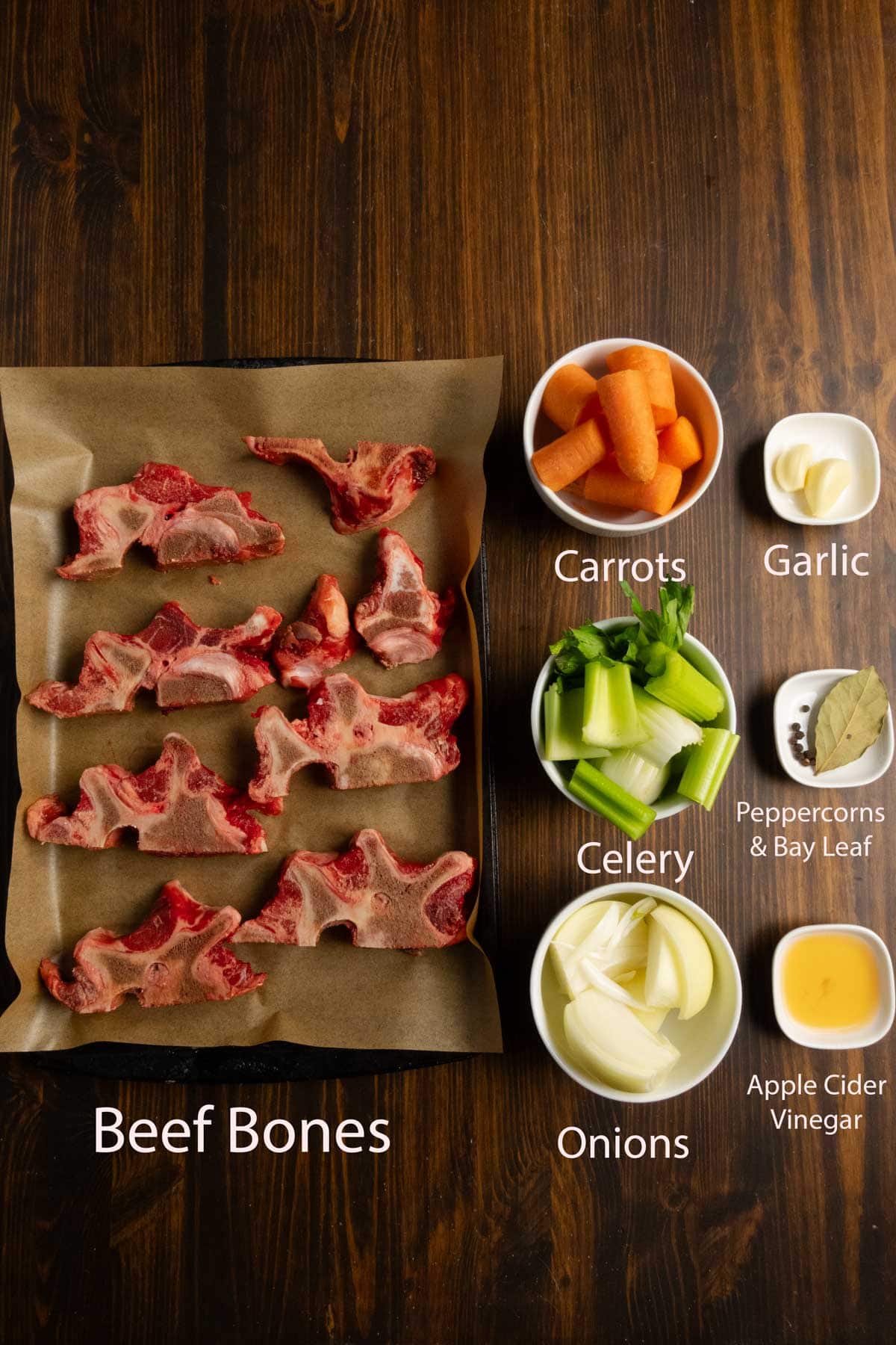 Ingredient shot of beef neck bones, carrots, celery, onions, garlic, bay leaf, peppercorns, and apple cider vinegar.