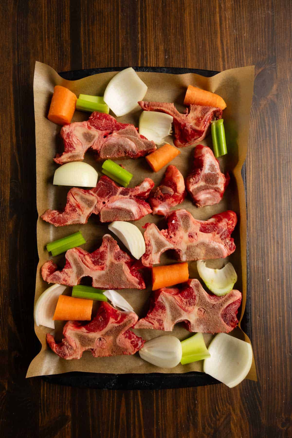 Beef neck bones and vegetables on a sheet pan before roasting.