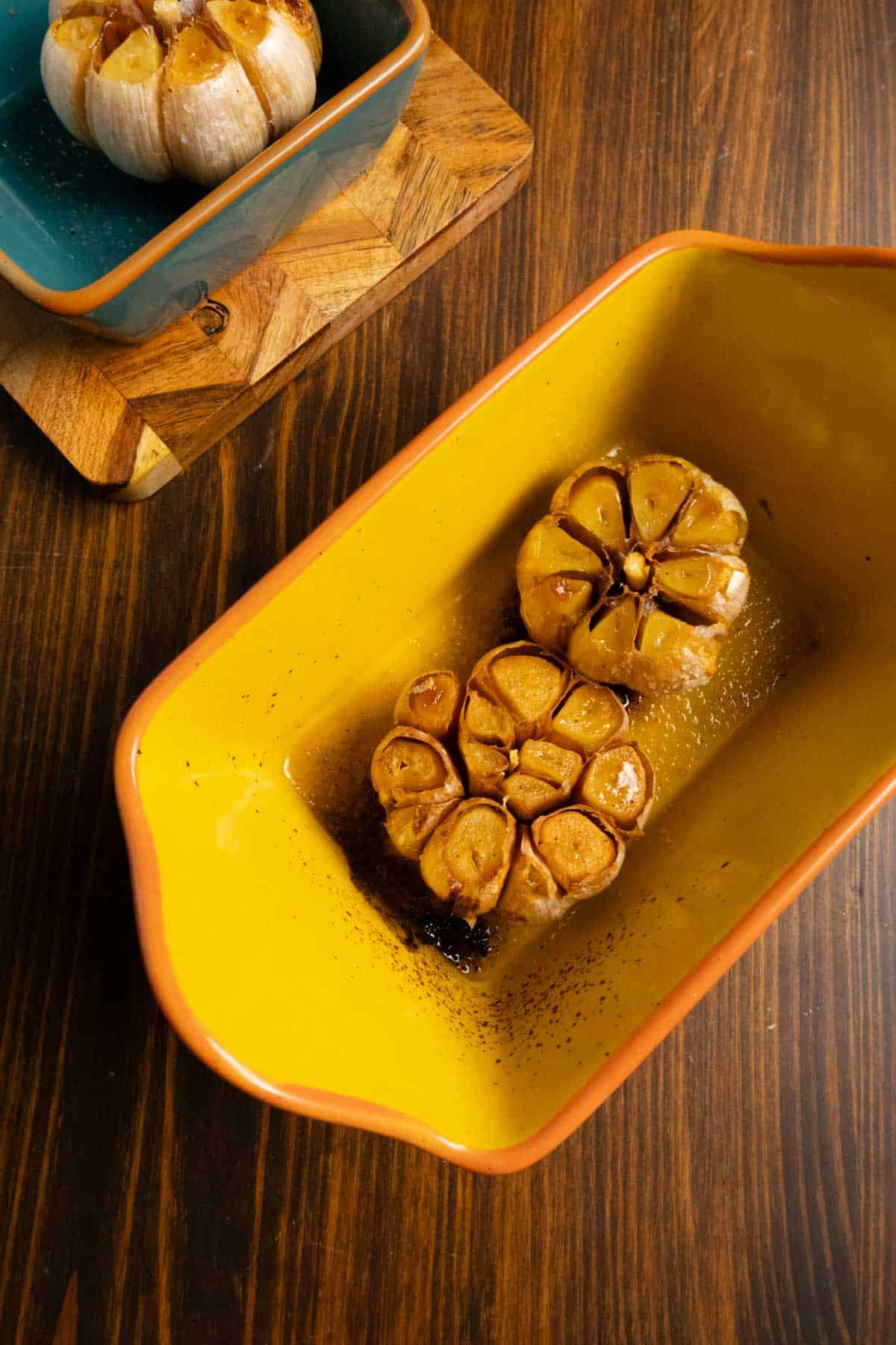 A pan with two beautifully roasted heads of garlic.