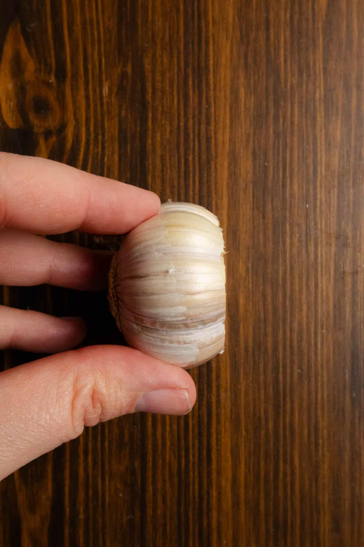 A garlic bulb with 1/2 inch cut off of the top on it's side to show how deeply to cut.