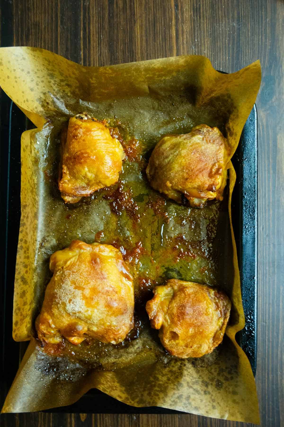 Crispy baked chicken thighs on a tray.