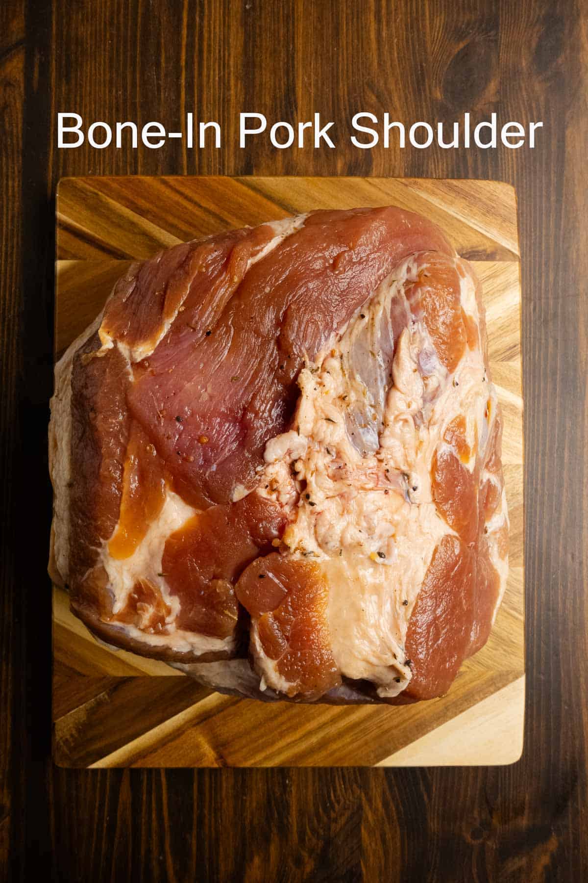 A bone in pork shoulder that weighs 9 pounds on a cutting board.