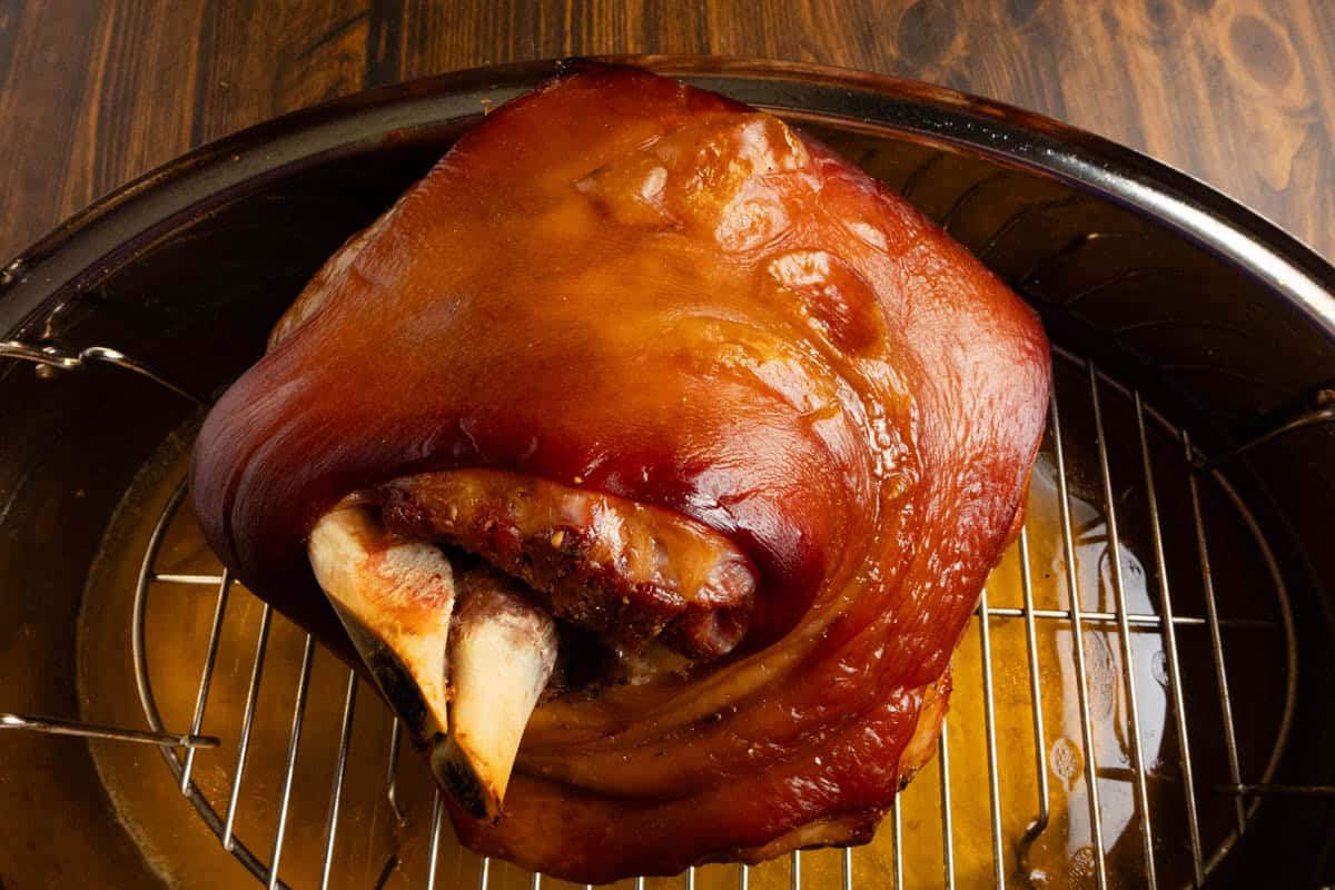 A roasting pan with a rack with a fully cooked ham on it.